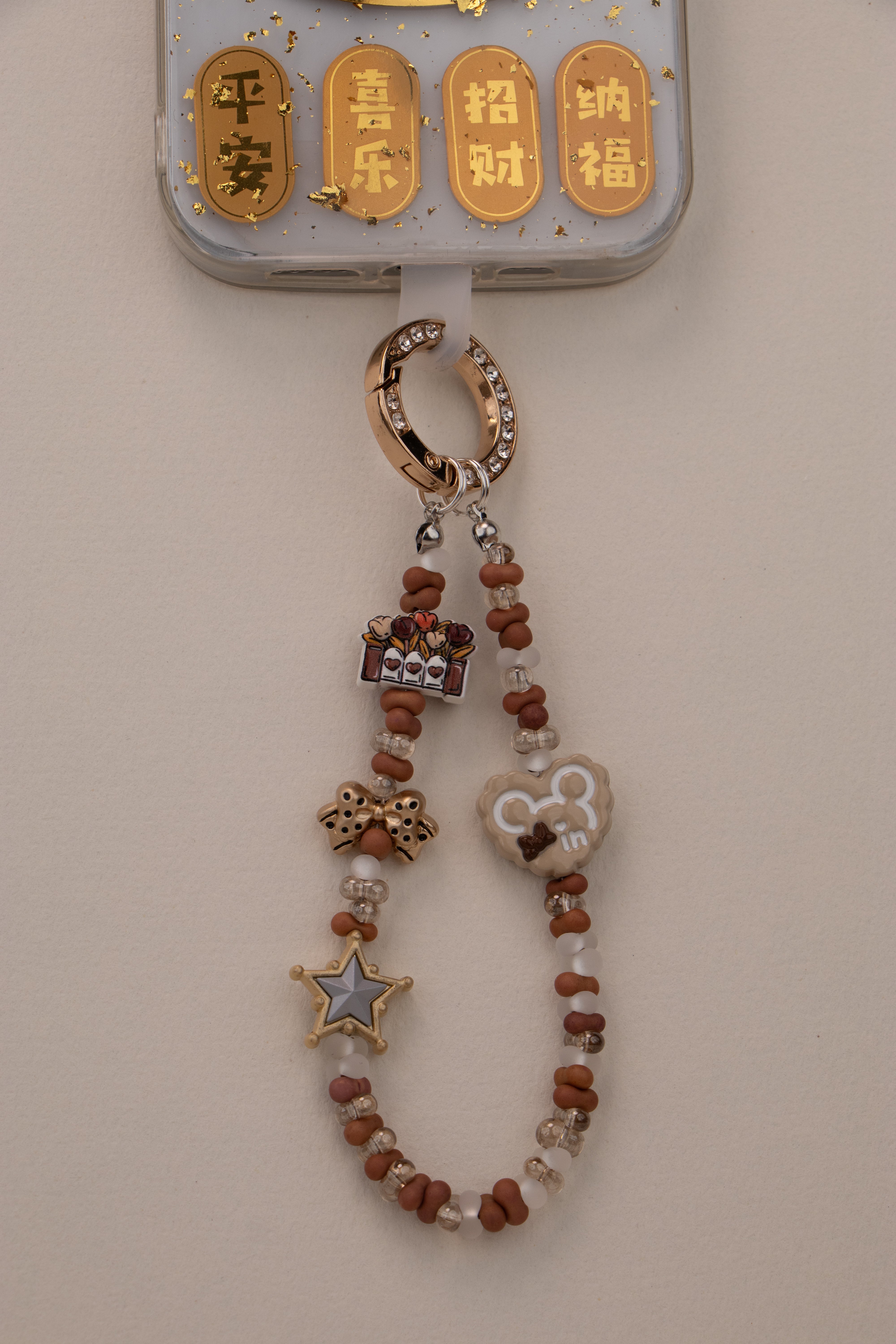 Little Luck beaded phone charm with gold-tone rhinestone ring on white background
