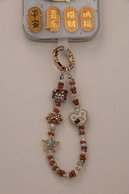 Little Luck beaded phone charm with gold-tone rhinestone ring on white background