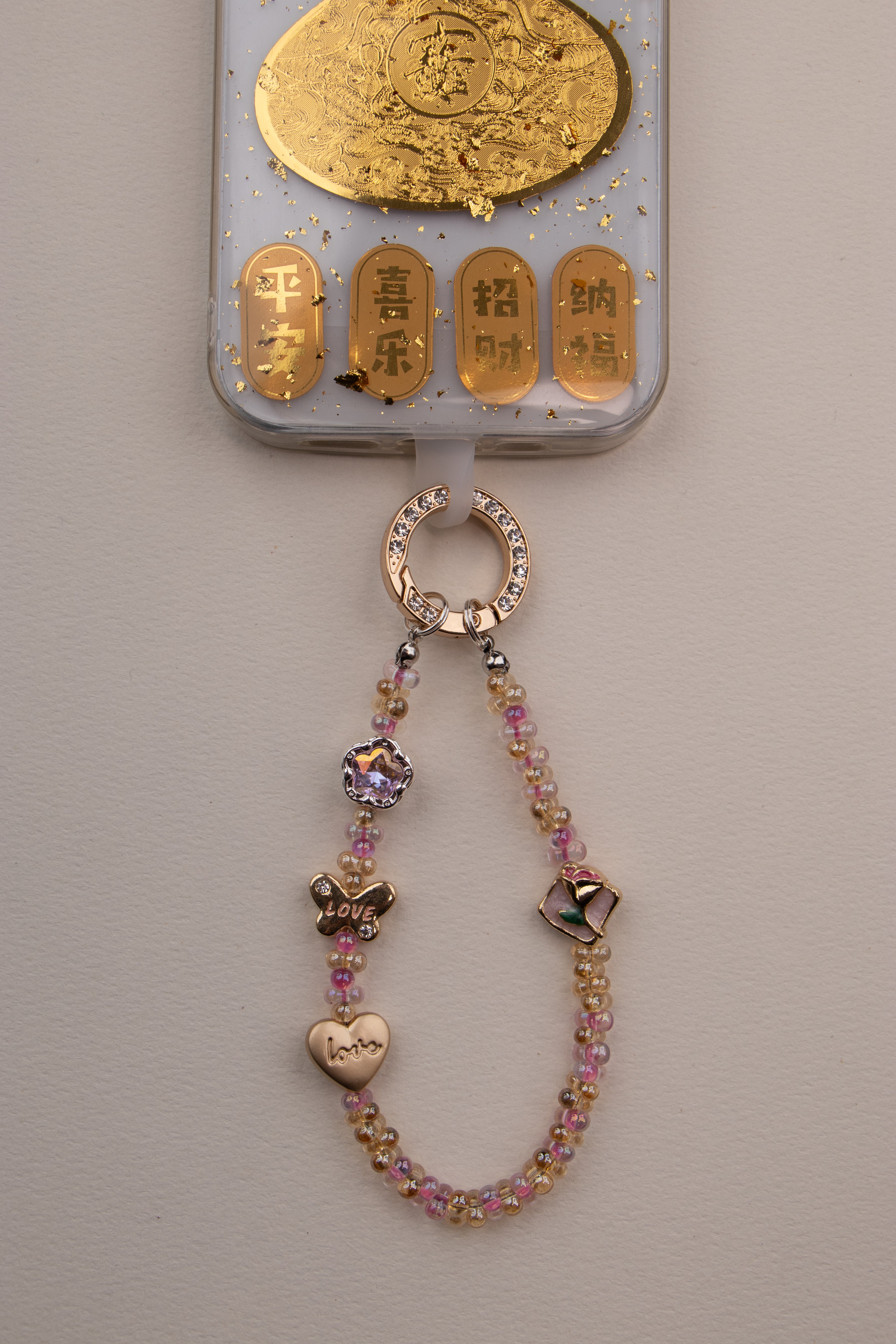 Soft Love beaded phone charm with gold-tone rhinestone ring on white background