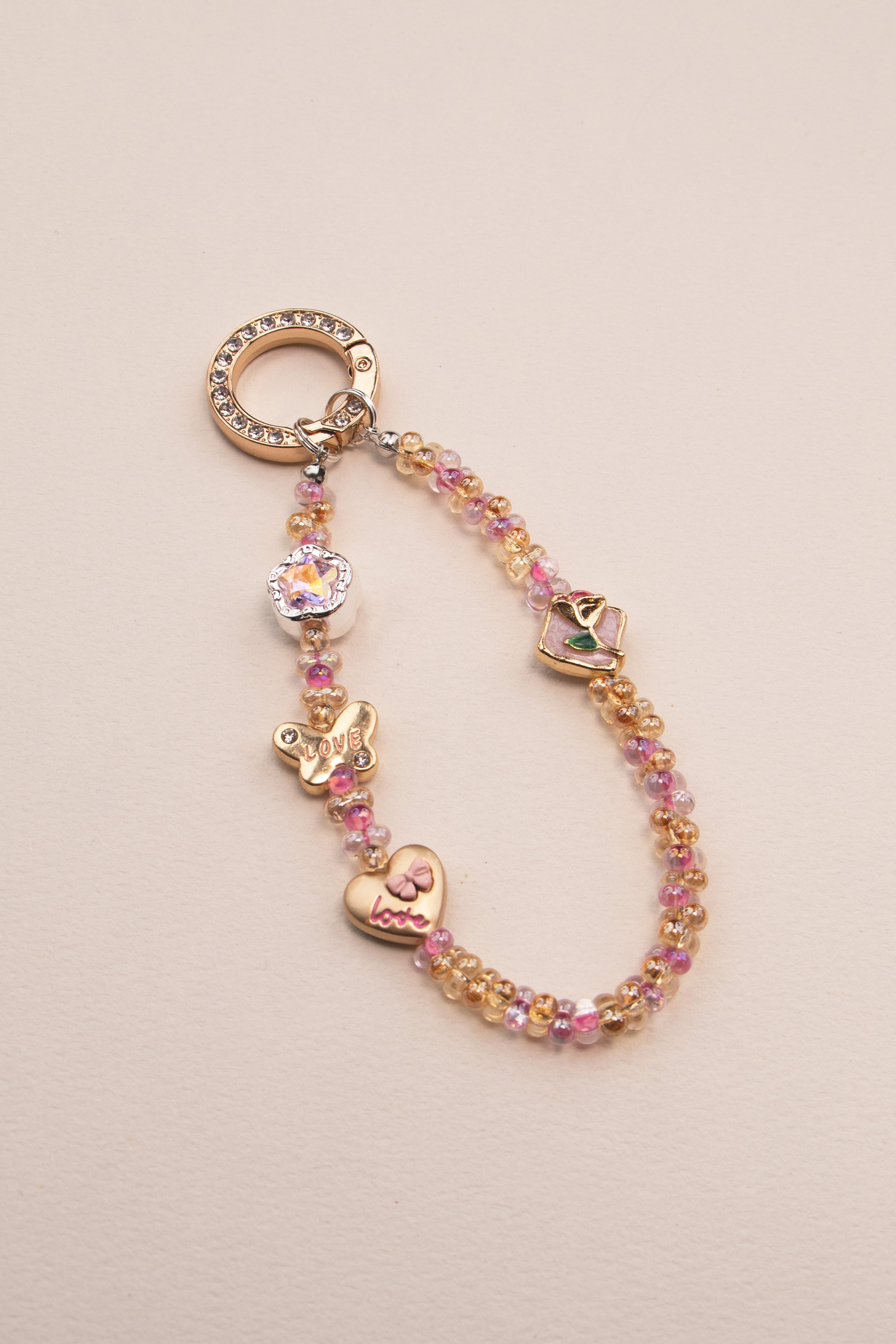 Soft Love beaded phone charm with pink and gold beads on neutral background