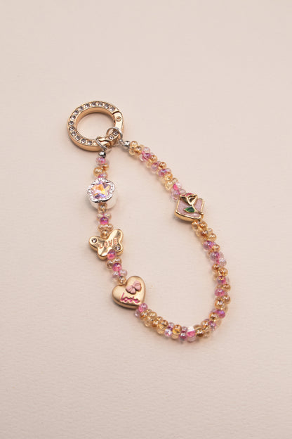 Soft Love beaded phone charm with pink and gold beads on neutral background