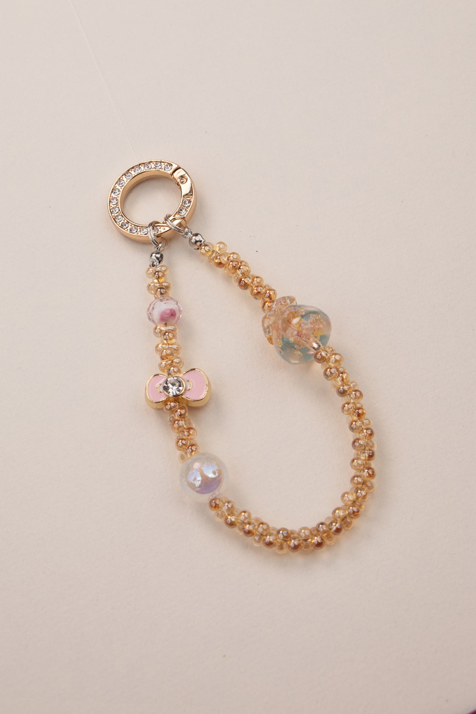 Golden Bloom beaded phone charm with warm golden beads on white background