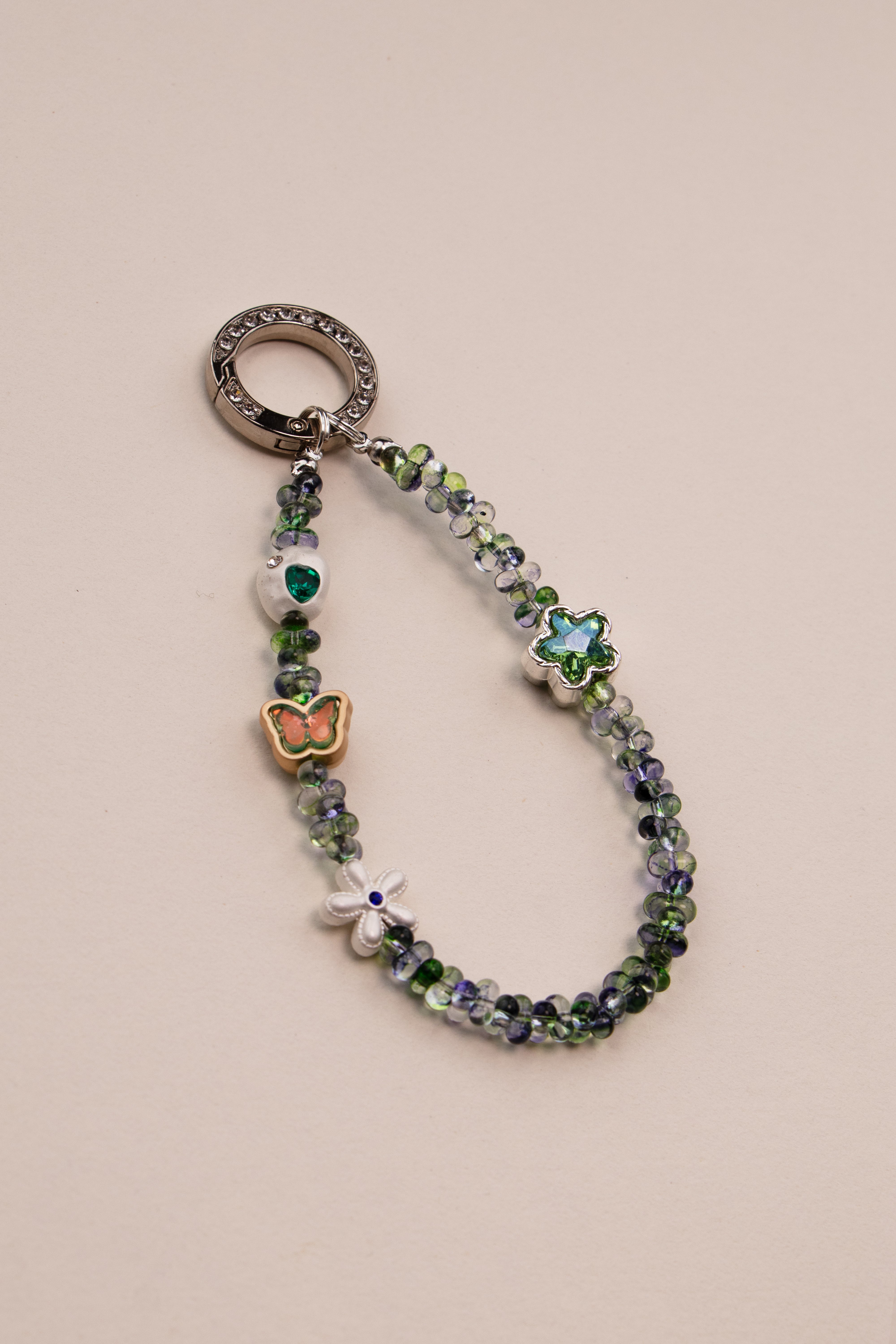 Green Whisper beaded phone charm with green beads on neutral background