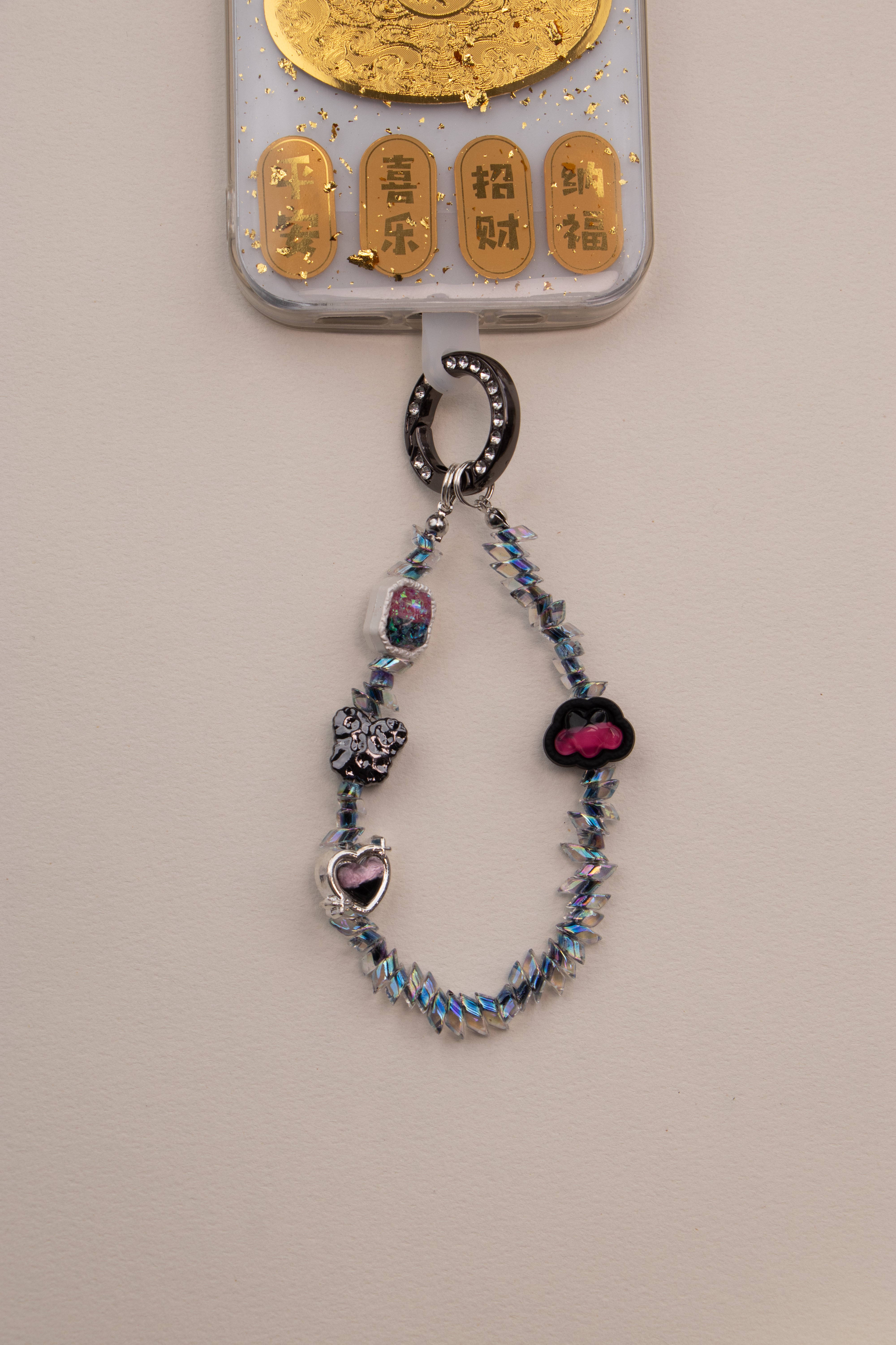 Midnight Flutter beaded phone charm with dark ring on neutral background
